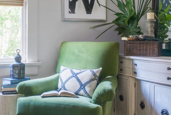 Cozy reading nook with a green velvet chair, abstract black-and-white art, and layered greenery styled by Nandina Home & Design.